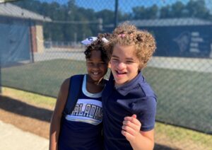 making a plan | Angelman Syndrome News | Juliana hugs her sister, Jessa, after a middle school football game. Juliana is wearing a navy polo shirt and Jessa is wearing her cheerleading uniform.